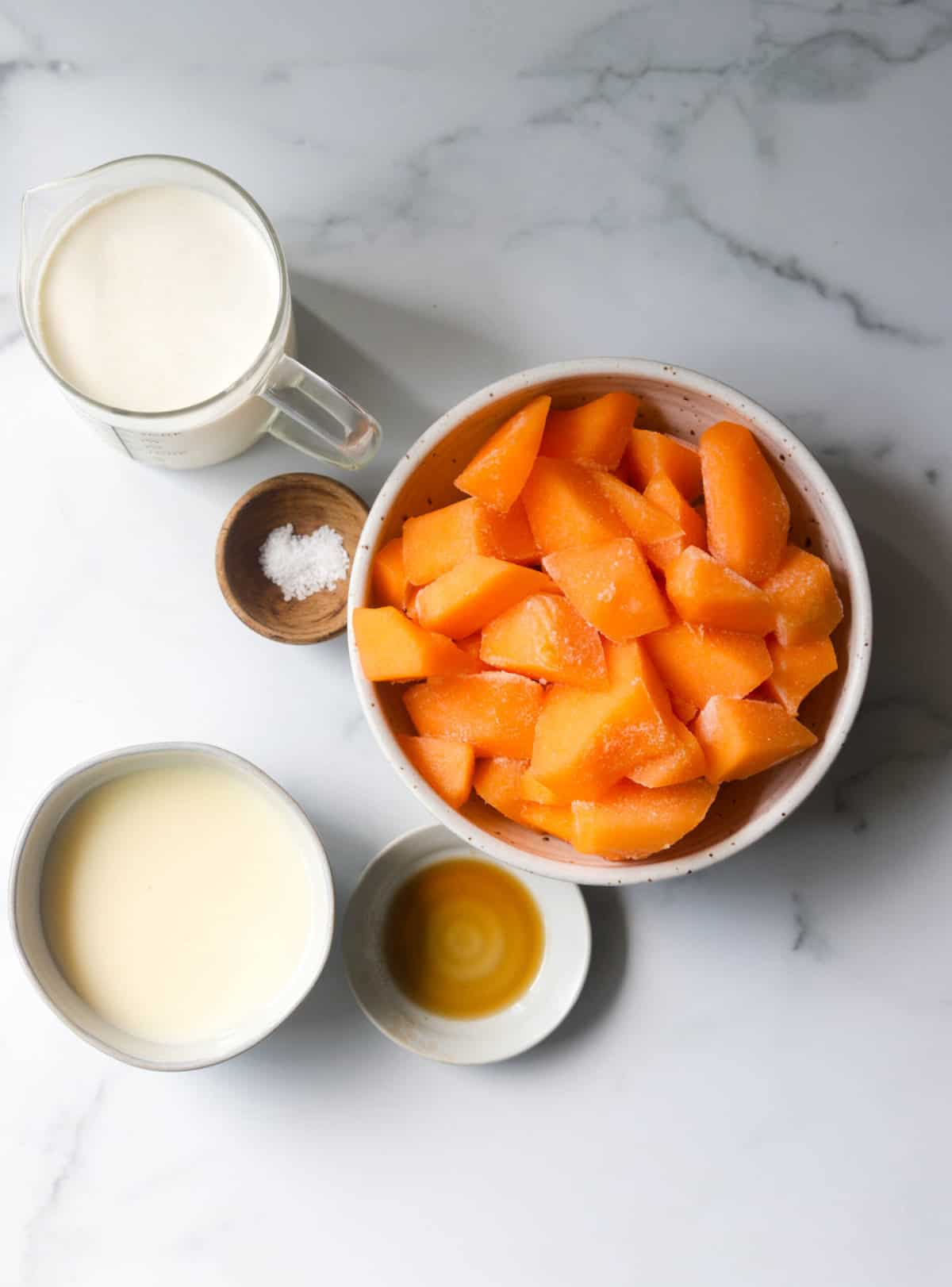 An overhead shot of bowls of ingredients to make cantaloupe ice cream.