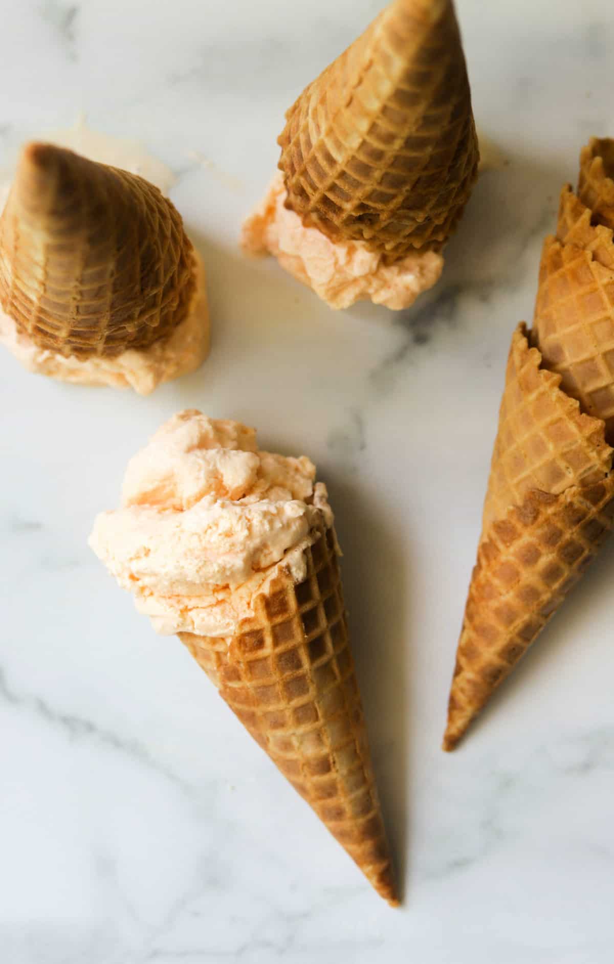 An overhead shot of a waffle cone with cantaloupe ice cream.