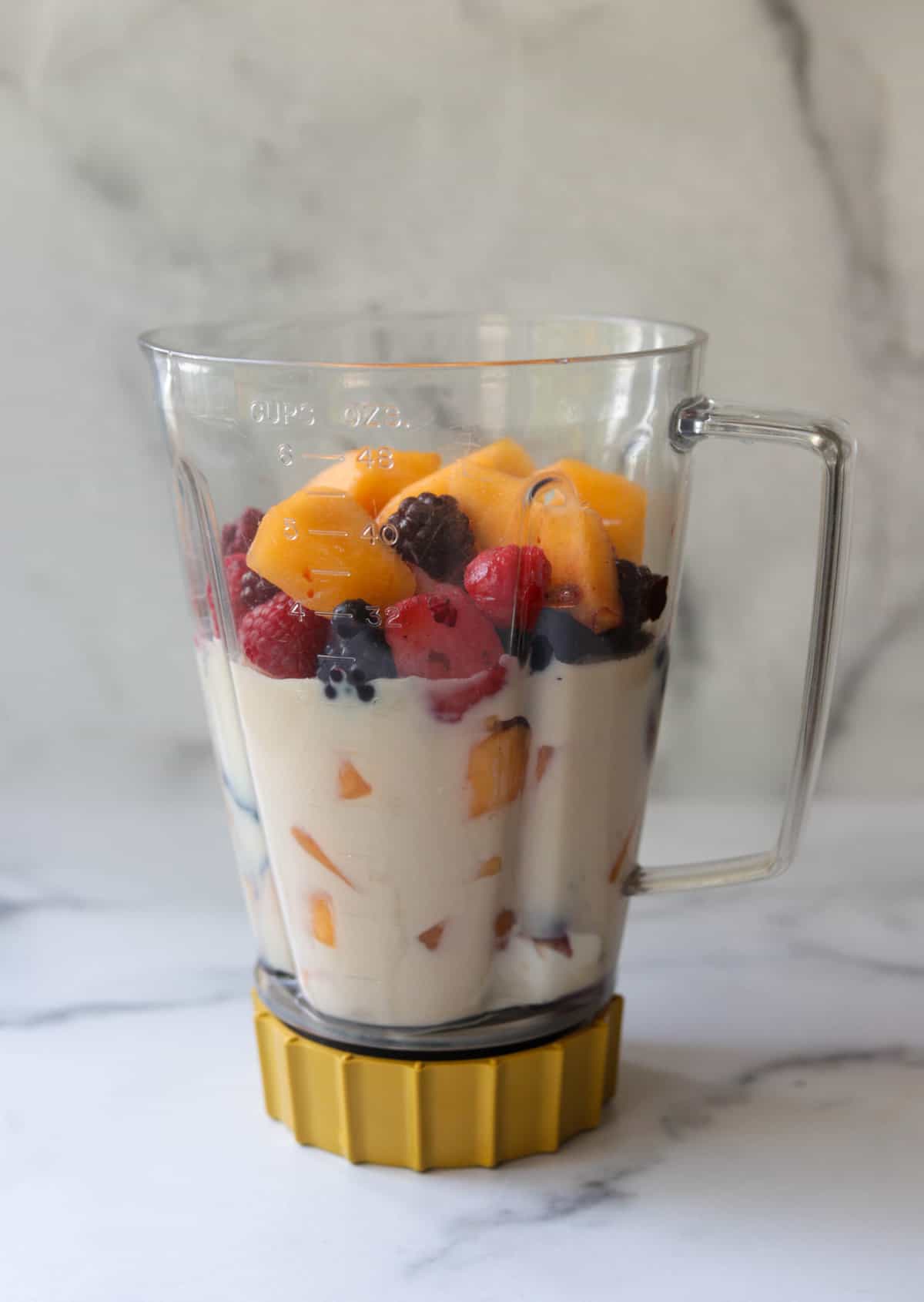 A side shot of a blender filled with smoothie ingredients.