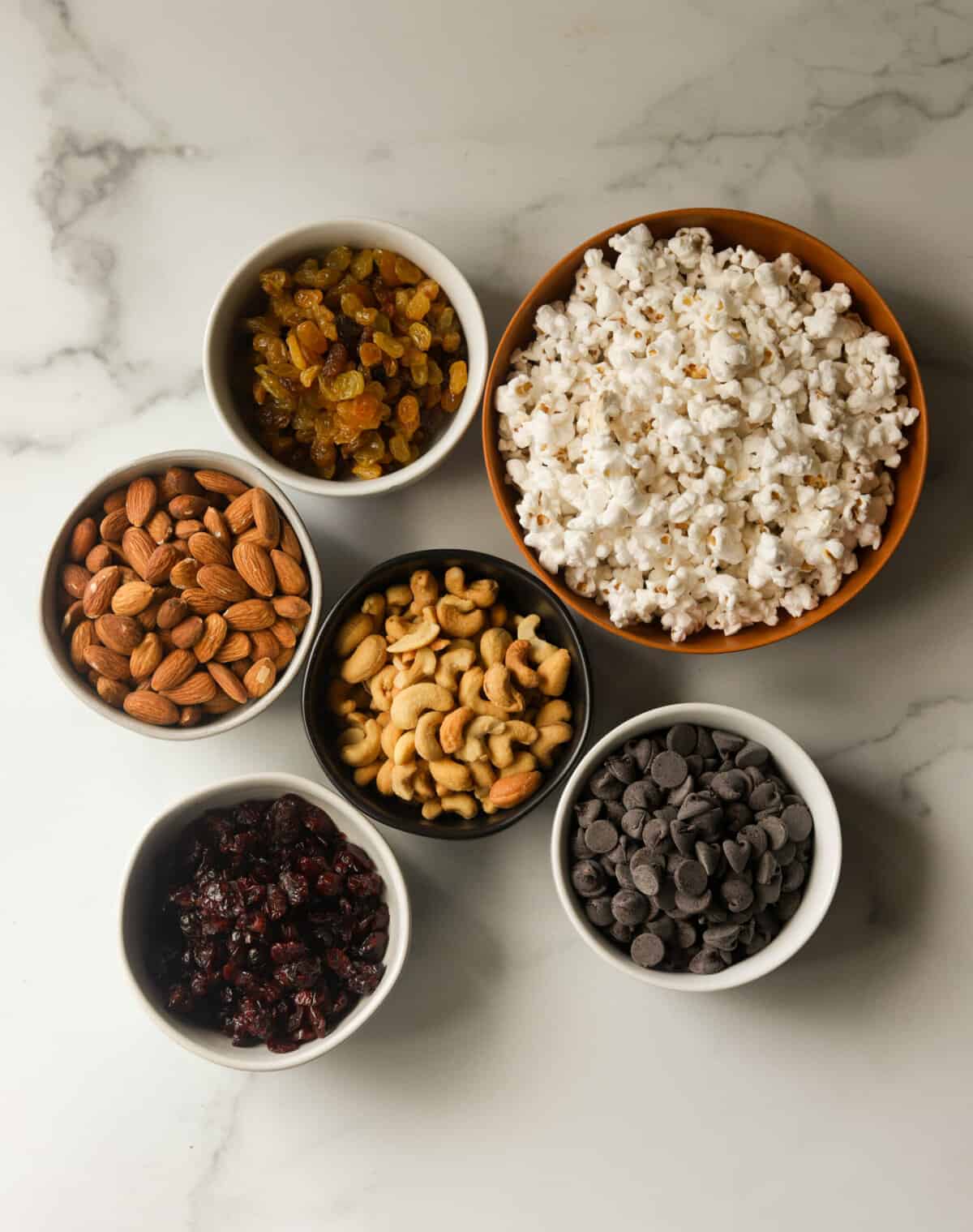 An overhead shot of small bowls filled with trail mix ingredients.