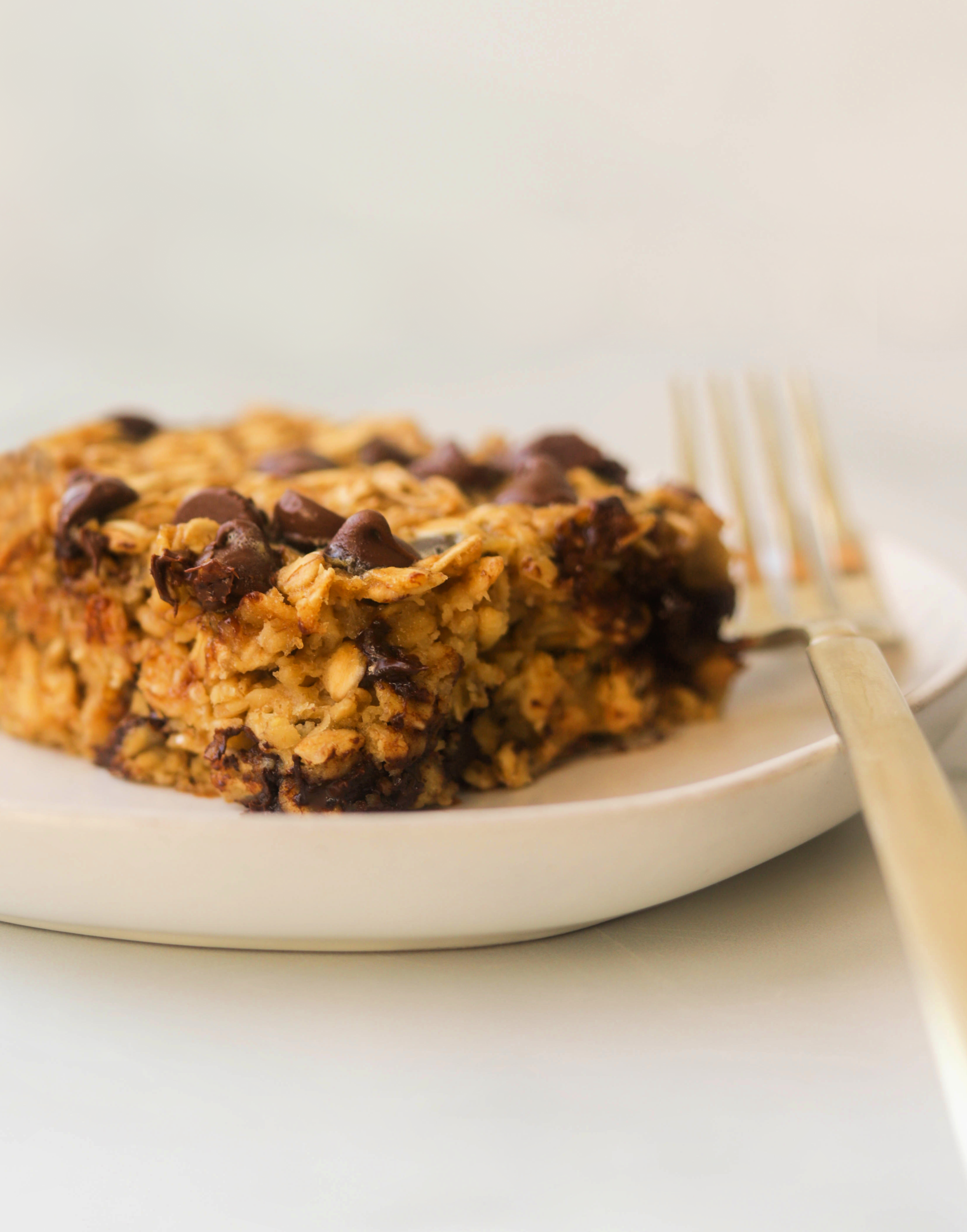 A side shot of chocolate chip baked oats on a white plate with a fork.