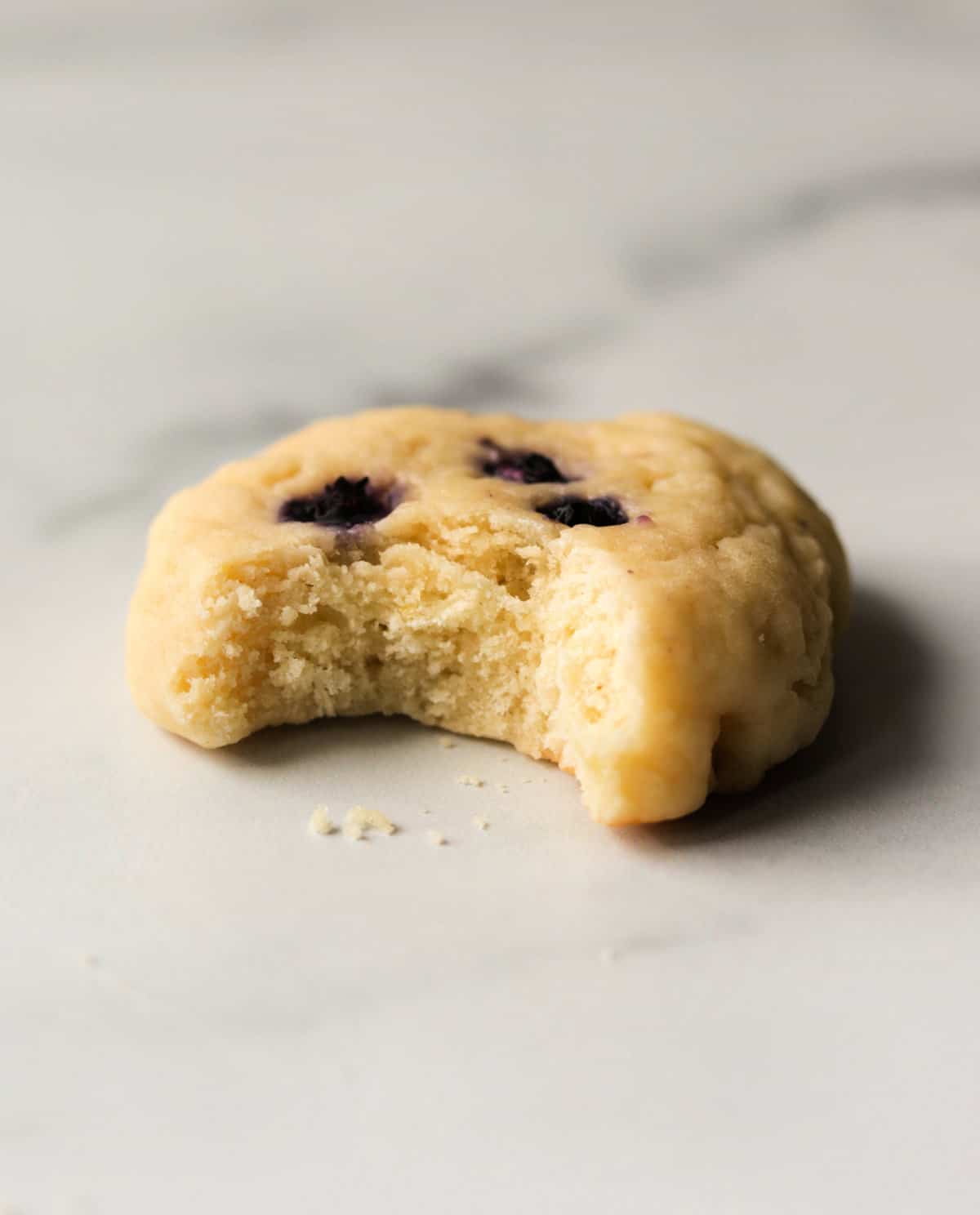 An angled shot of a lemon cookie with a bite taken out.