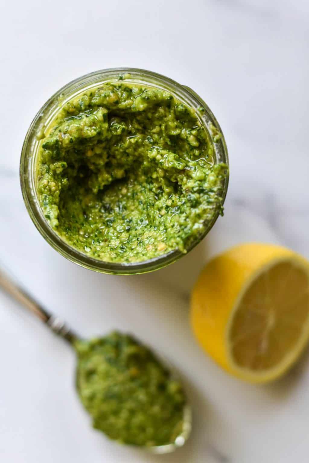 An overhead shot of a jar of spinach almond pesto.