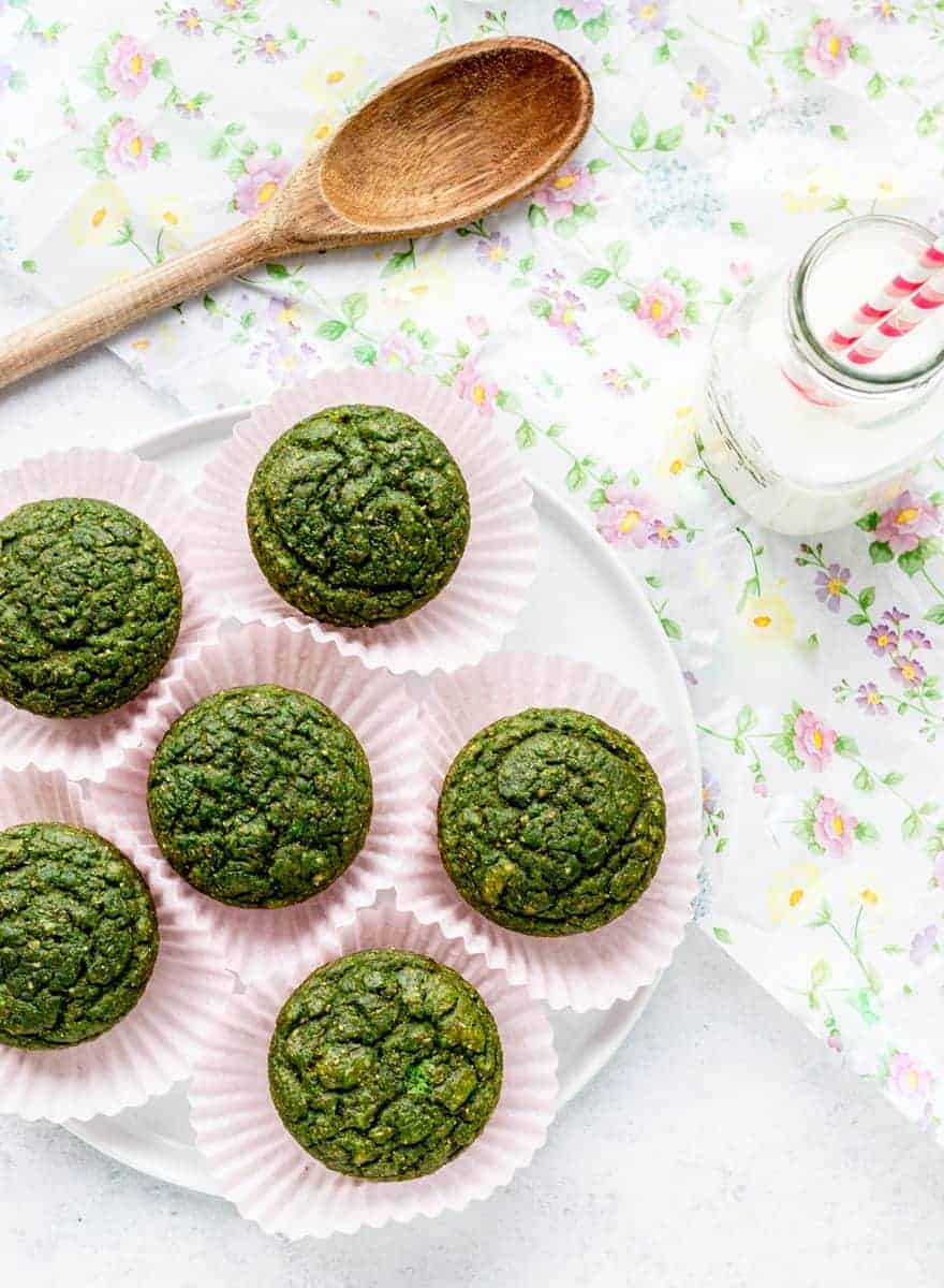An overhead shot of spinach muffins on a floral placemat.