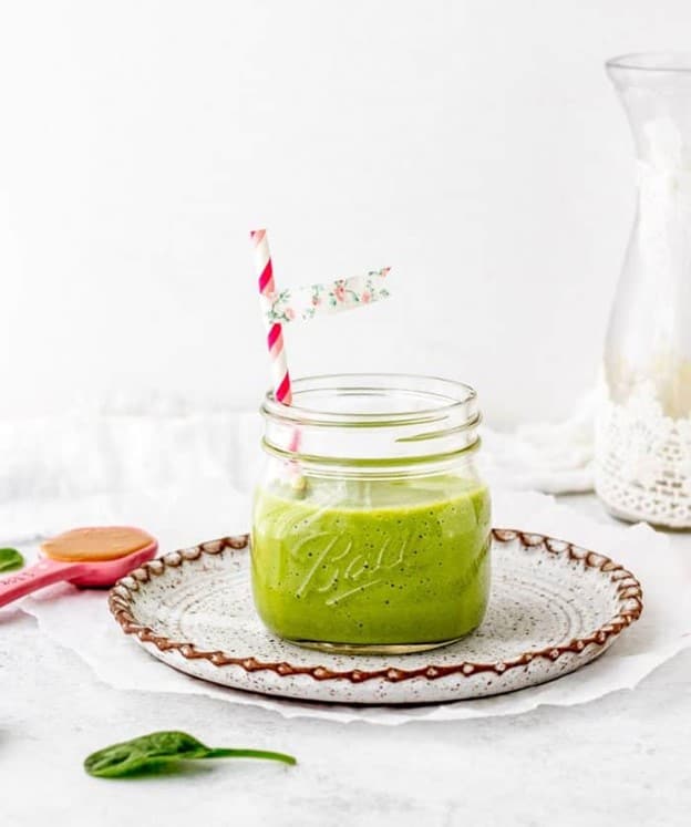 A front shot of a green smoothie in a ball jar.