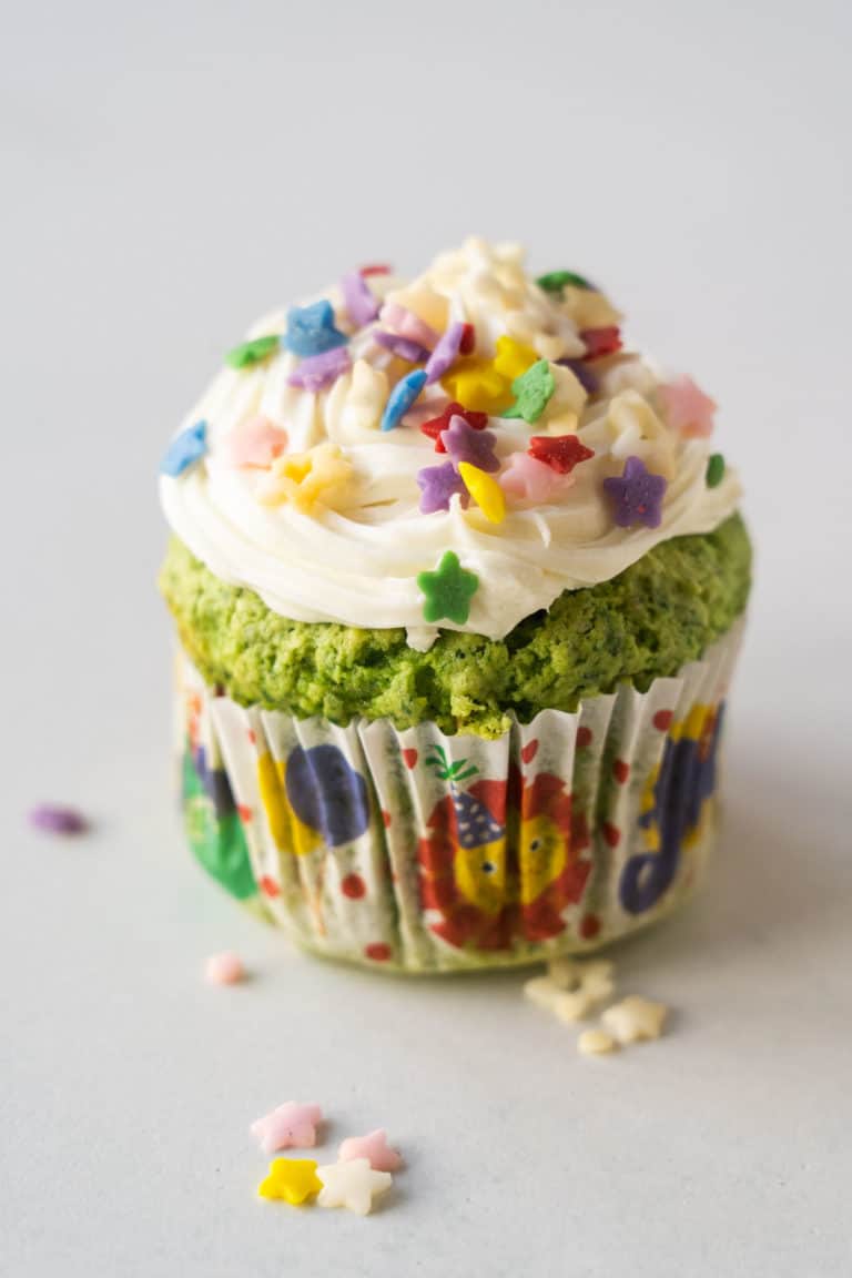 A front shot of a single spinach cupcake with sprinkles.