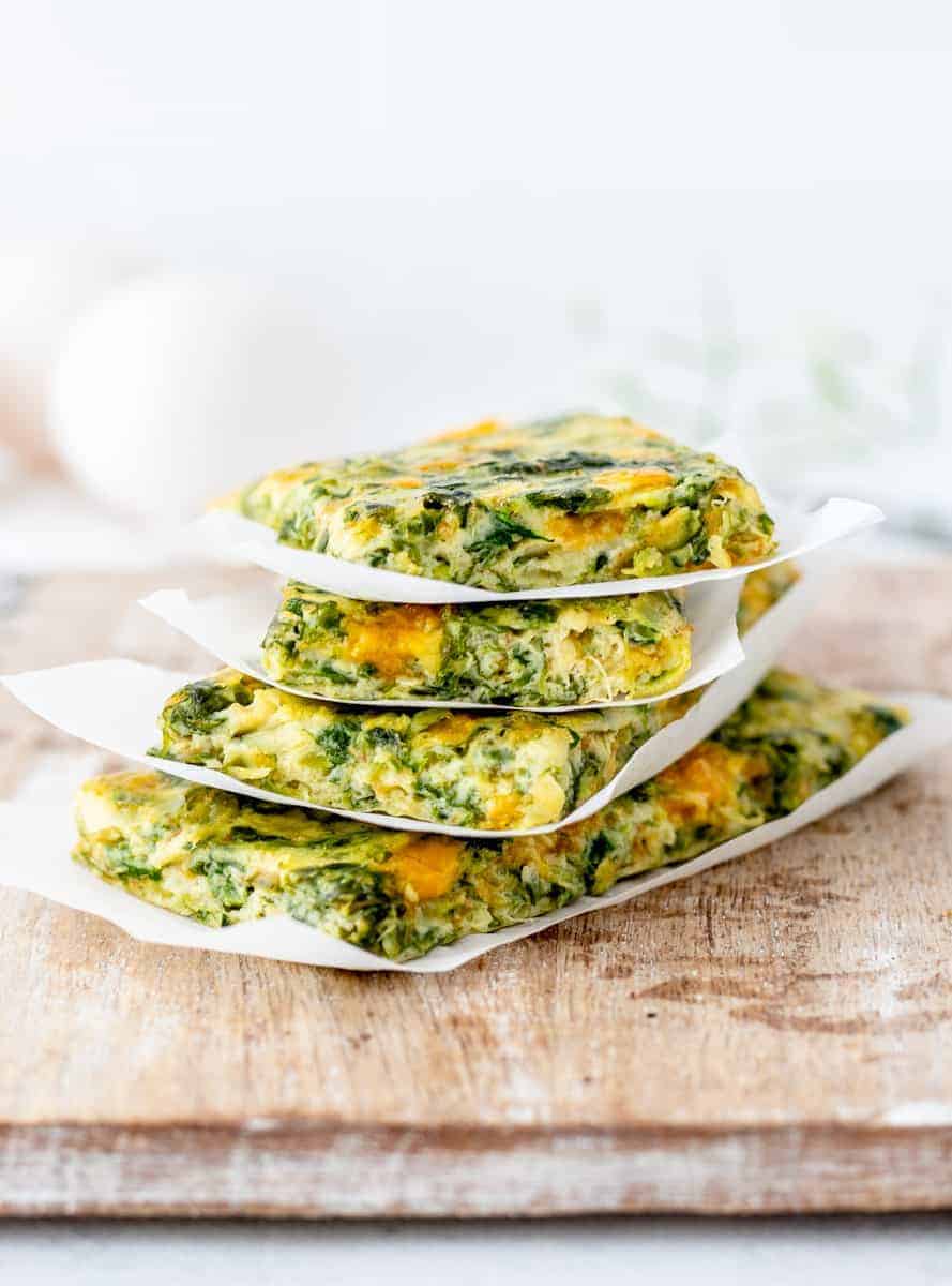 A side shot of spinach frittatas stacked.