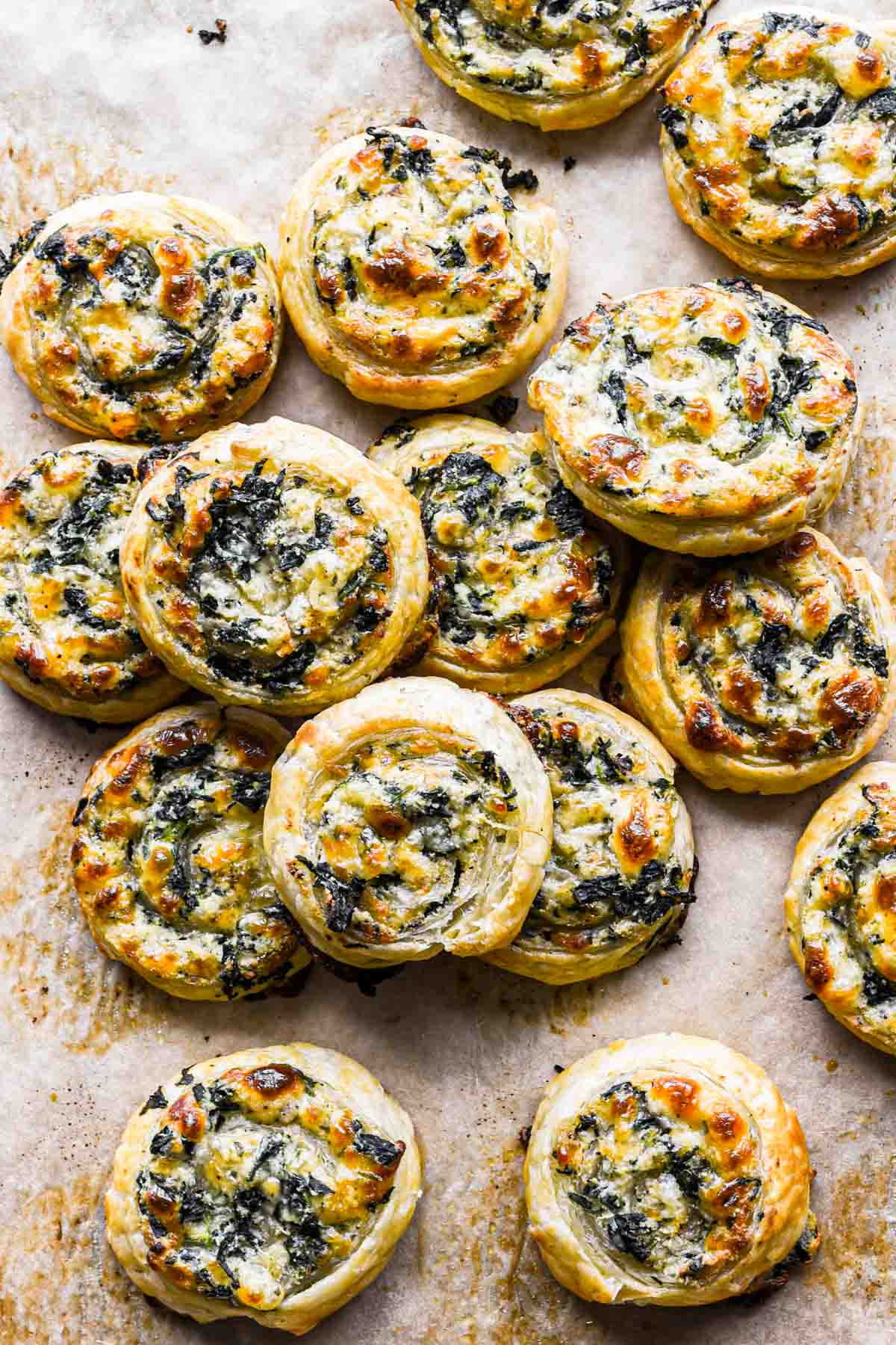 An overhead shot of spinach pinwheels on parchment paper.