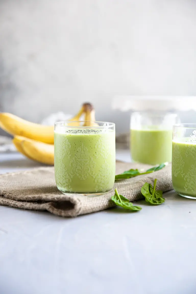 Three glasses filled with green smoothie.