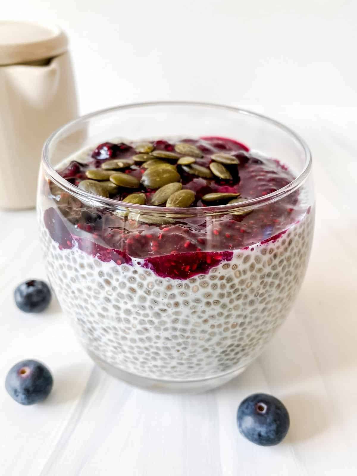A side shot of a jar of chia pudding with pepitas on top.