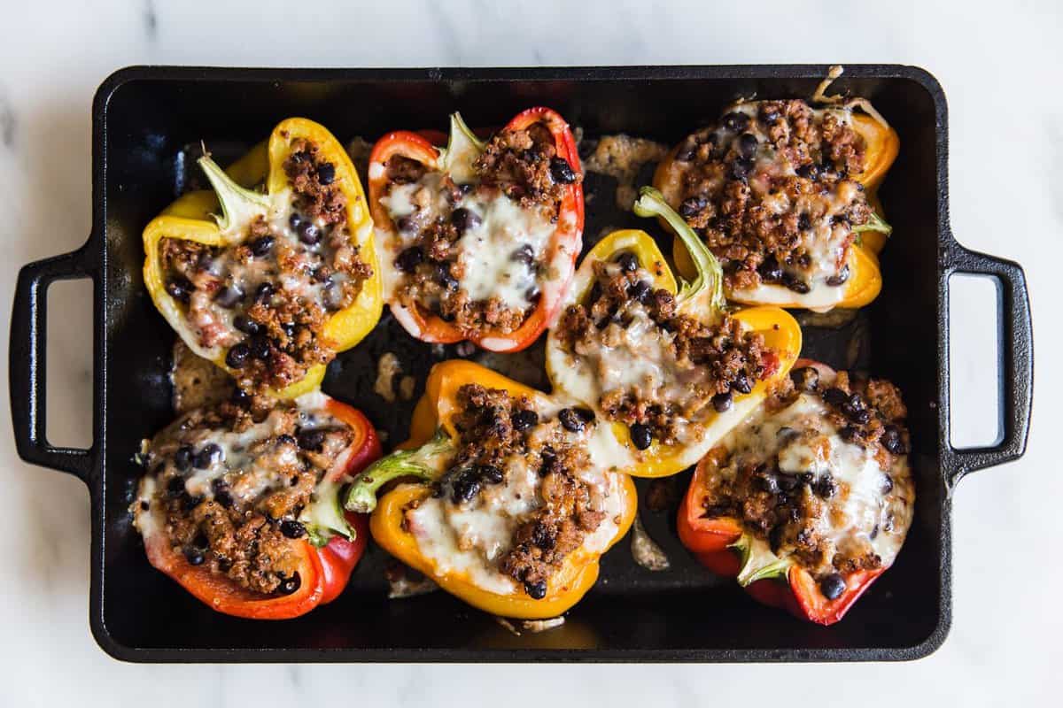 An overhead shot of a cast iron pan filled with stuffed bell peppers.