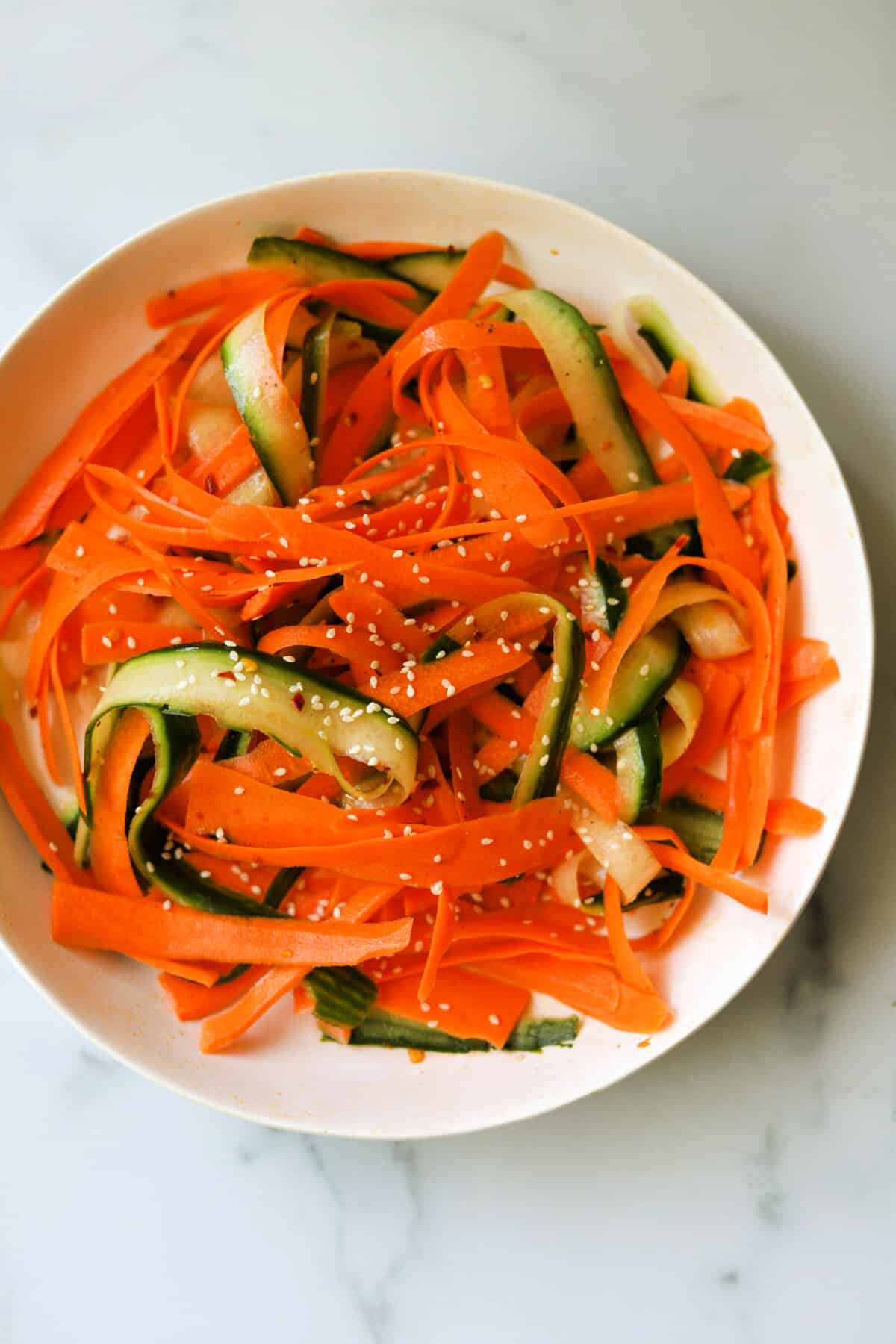 An overhead shot of a bowl of carrot and cucumber salad.