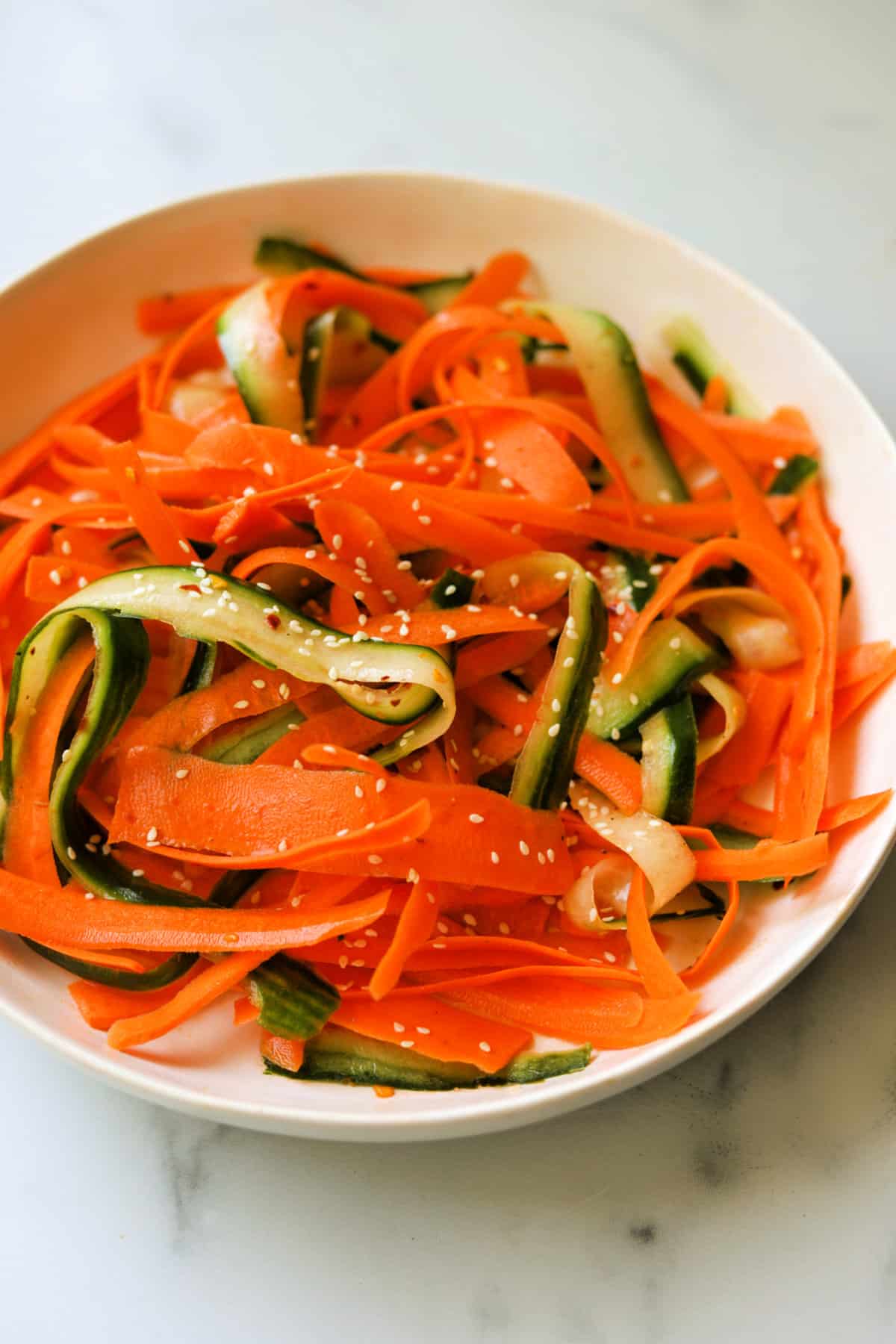 A side shot of a bowl of carrot cucumber salad.