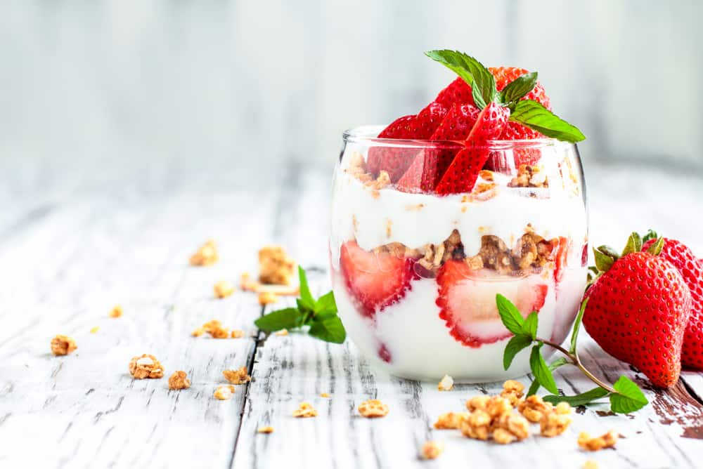 A side shot of a layered strawberry yogurt parfait.