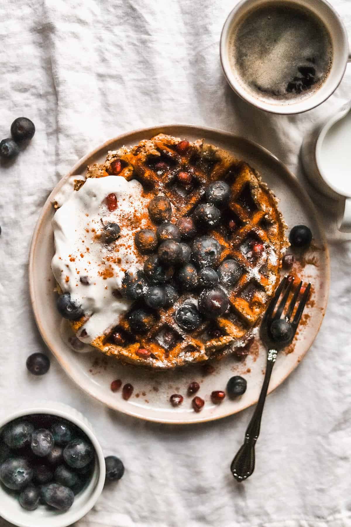 An overhead shot of a plate of sweet potato waffles with berries and yogurt.