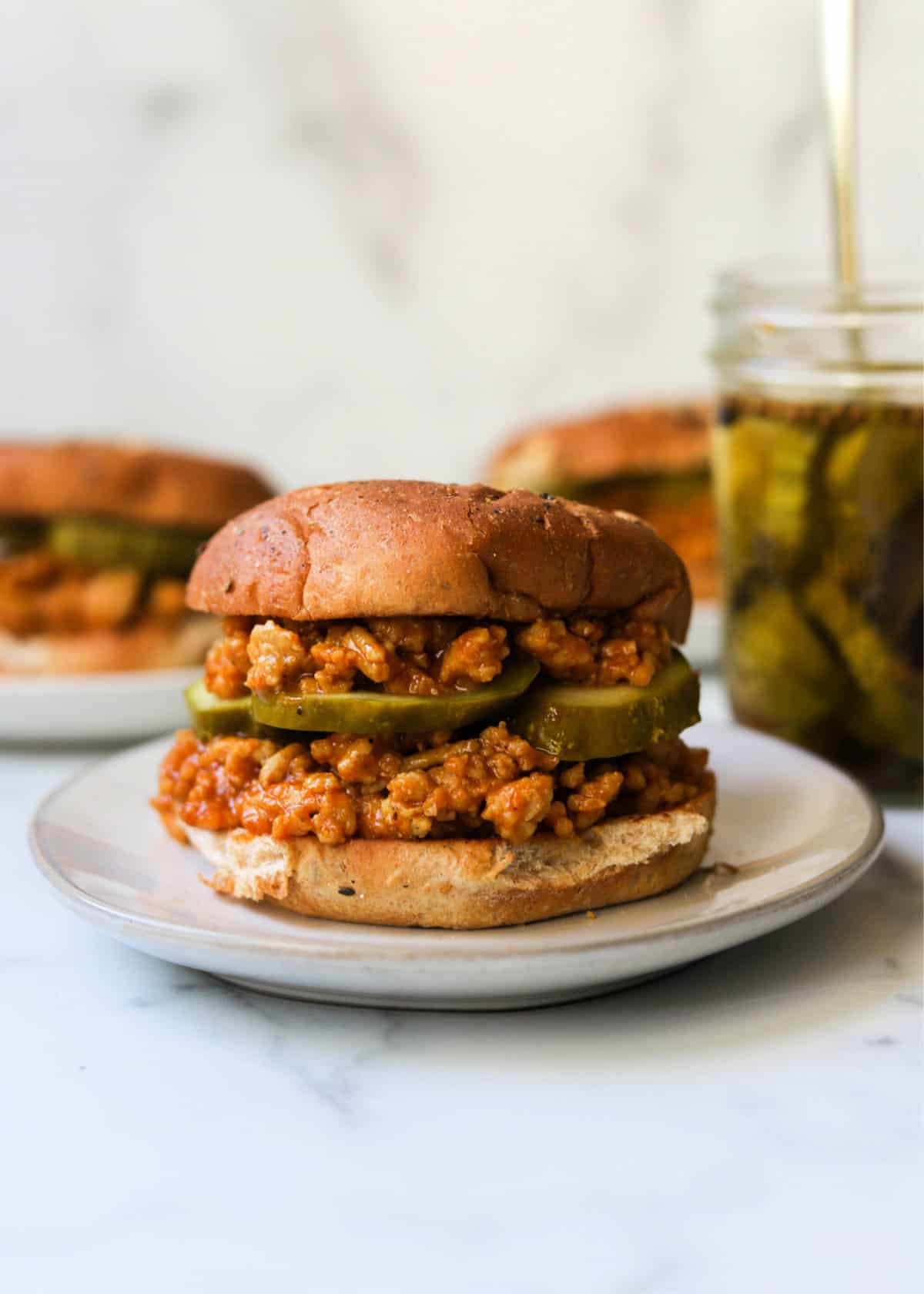 A front shot of a ground chicken sloppy joe with pickles.