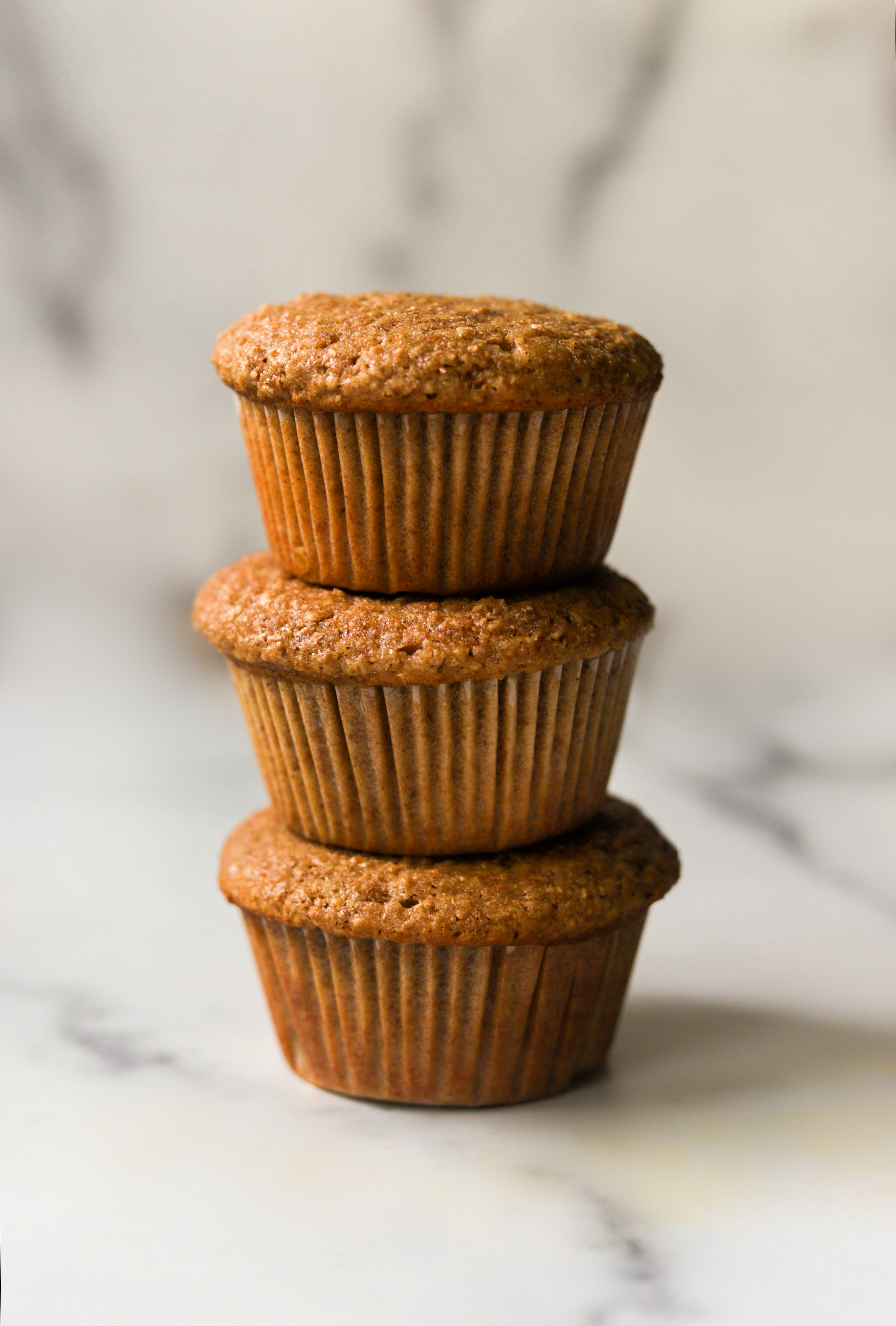A front shot of 3 bran muffins stacked on top of each other.