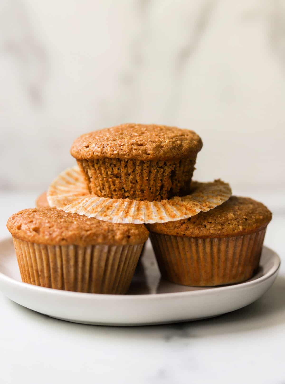 A front shot of stacked honey bran muffins on a white plate.