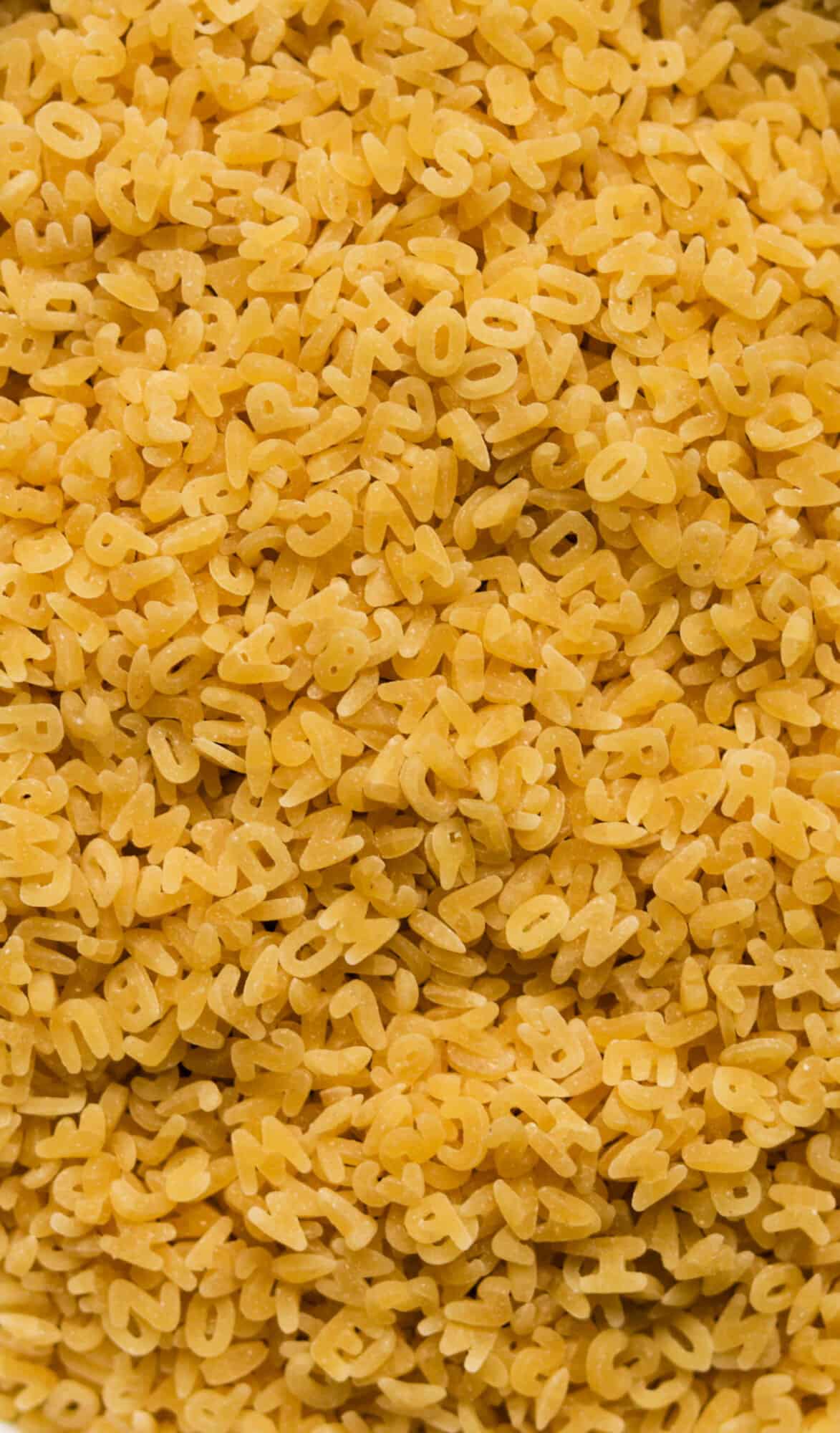 A close up overhead shot of uncooked alphabet pasta.