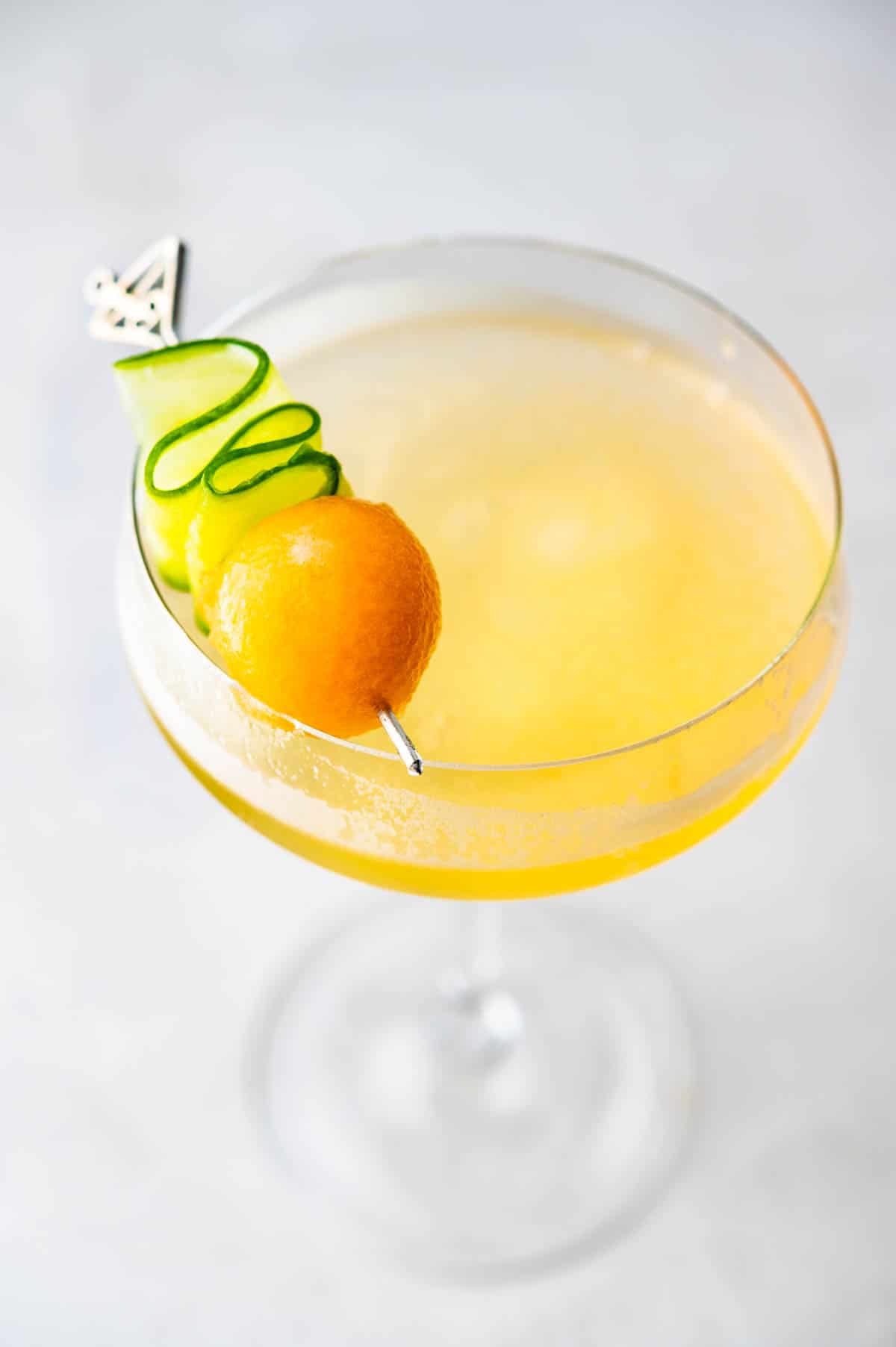 A front angled shot of a melon prosecco drink with a garnish on top.