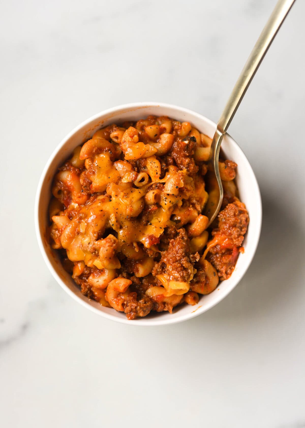 An overhead shot of a bowl of cheesy goulash.