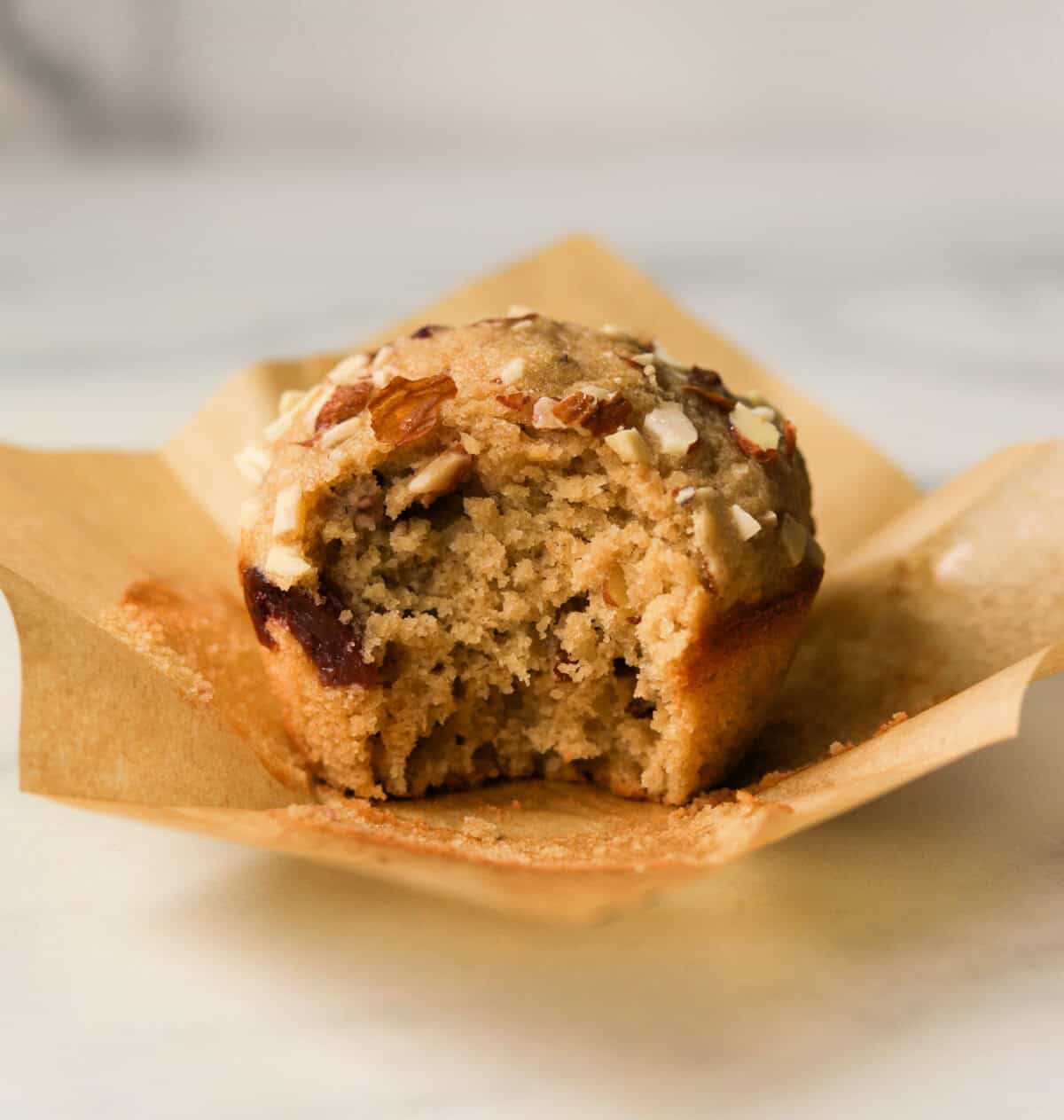 A front shot of a single cherry almond muffin with a bite taken out of it.