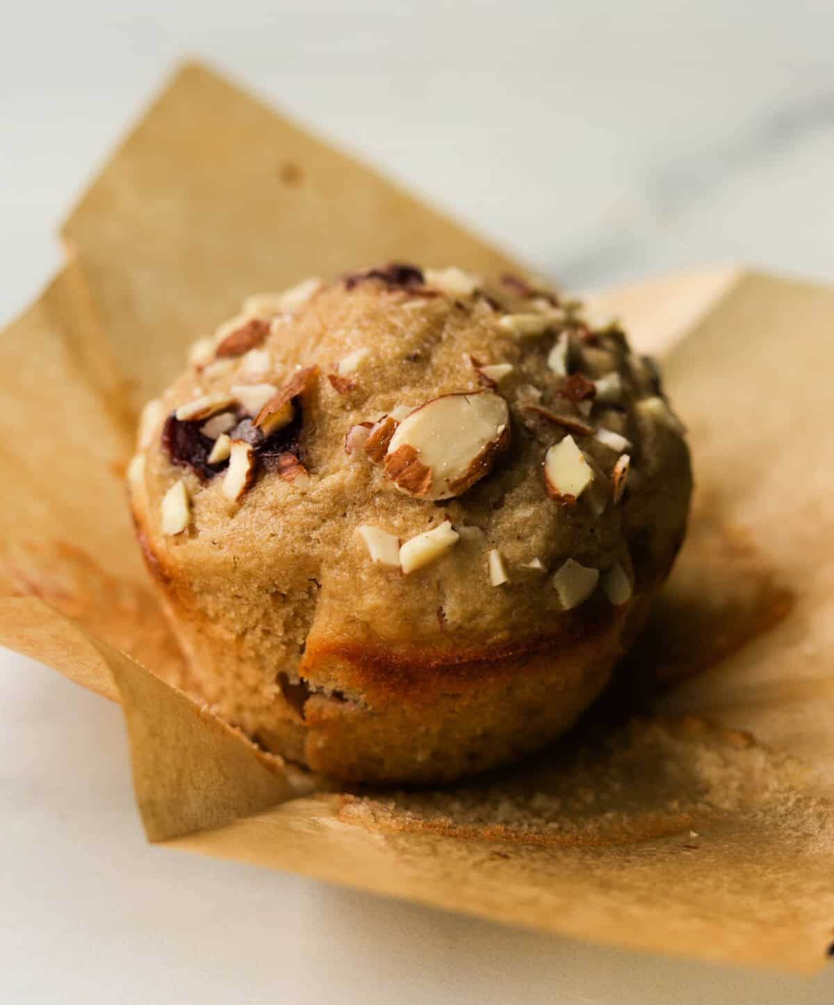 A front close up shot of a cherry almond muffin in a wrapper.