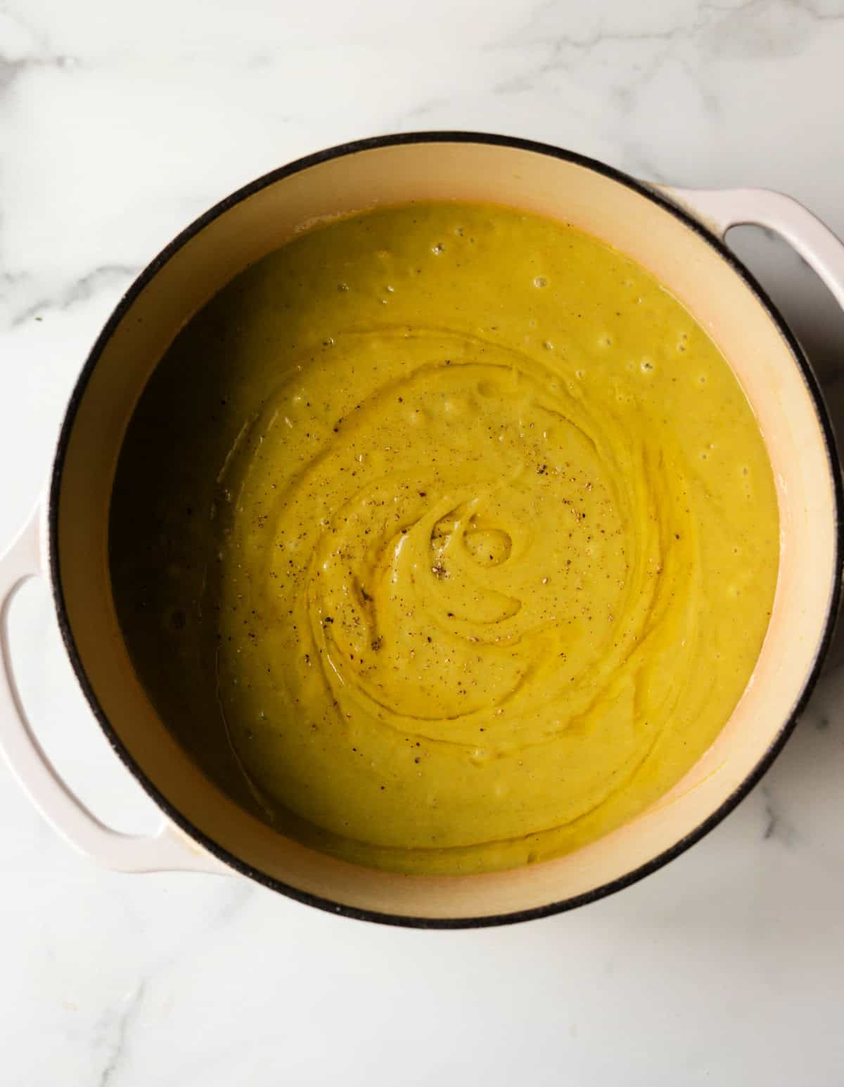An overhead shot of a pot of pureed potato asparagus soup.