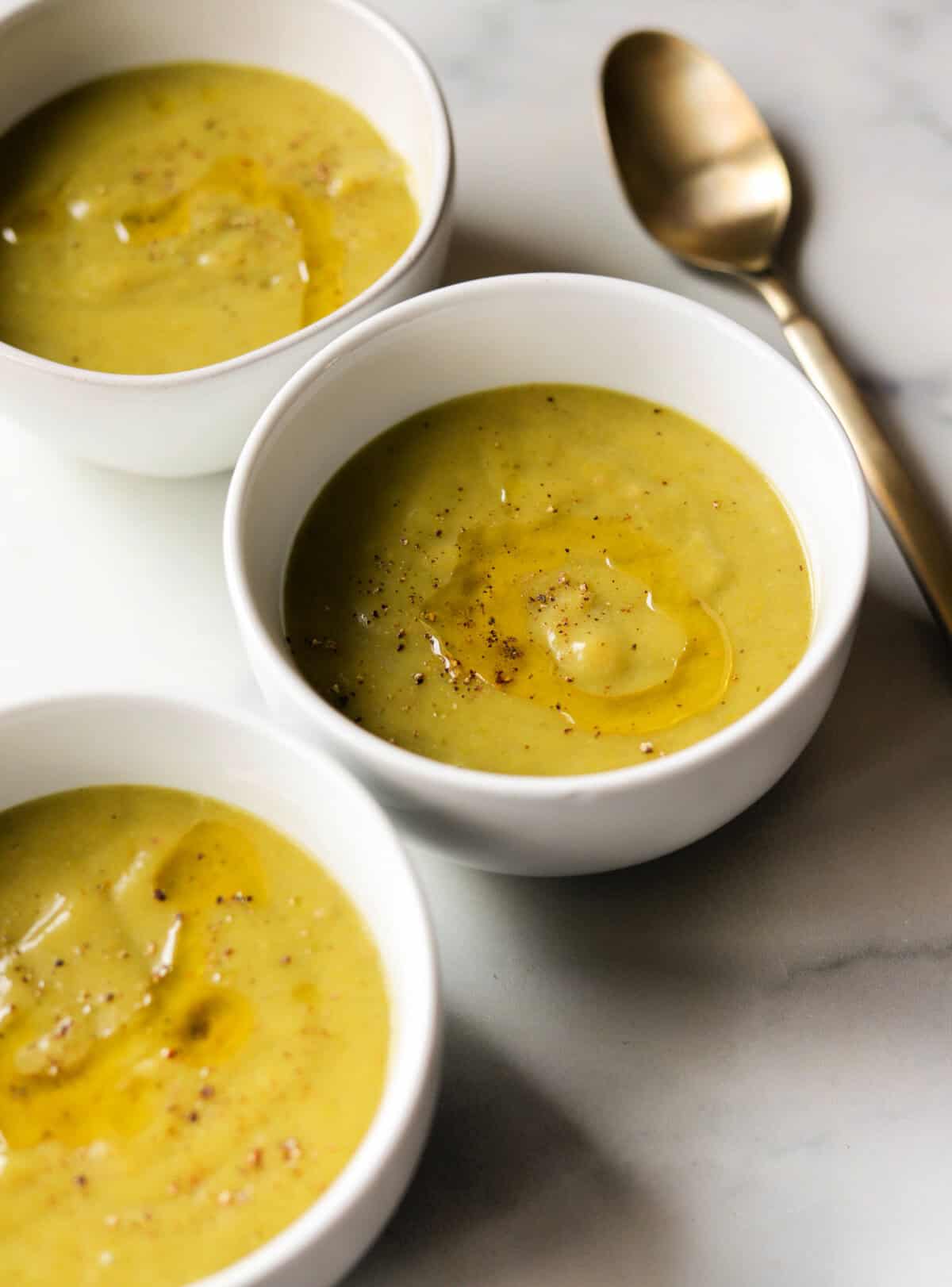 A front shot of 3 bowls of asparagus potato soup.