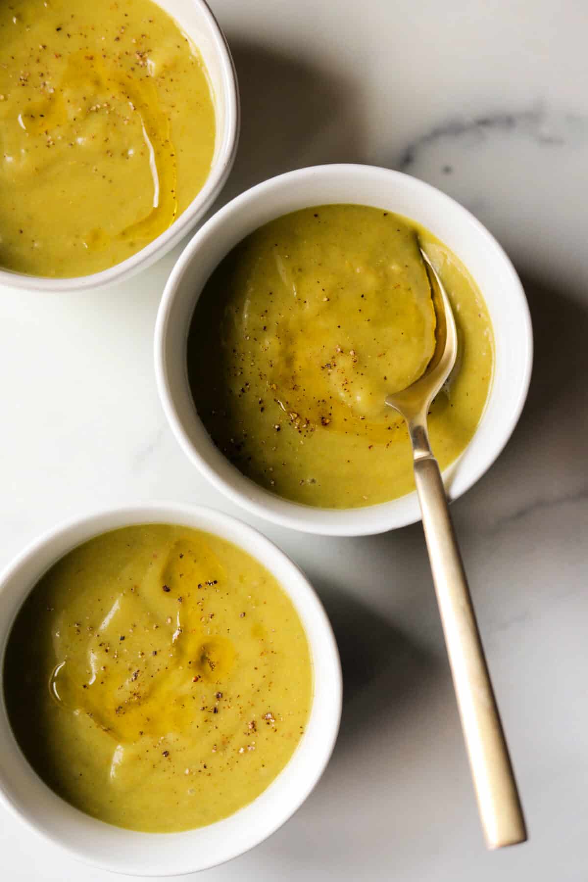 An overhead shot of 3 bowls of potato asparagus soup.