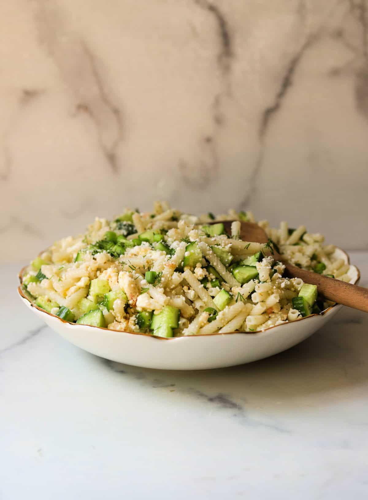 A front straight on shot of a bowl of cucumber feta pasta salad.