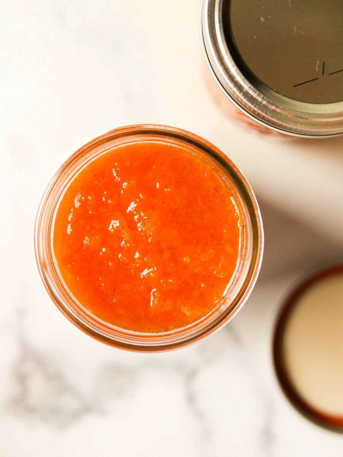 An overhead shot of a jar of fresh peach jam.